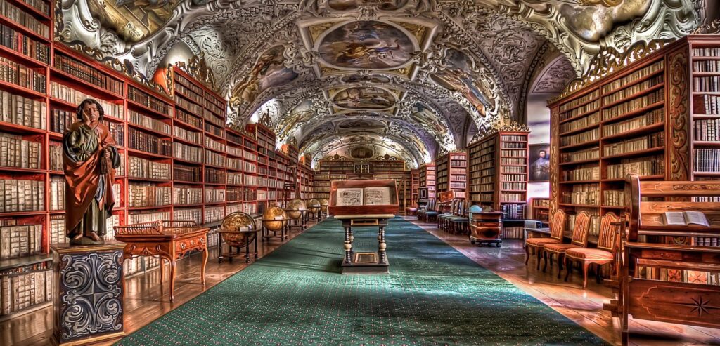 Historic European library hall with ornate ceiling frescoes, wooden bookshelves filled with manuscripts, and globes, symbolizing knowledge and discovery.